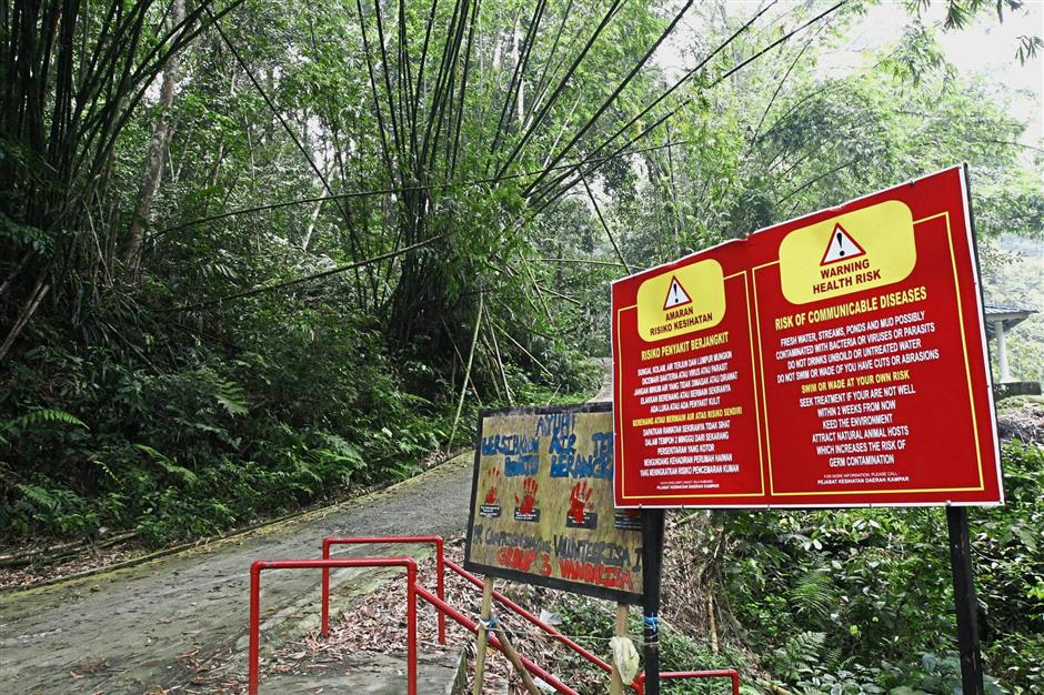 The Batu Berangkai waterfalls in Kampar with a sign warning of communicable diseases.