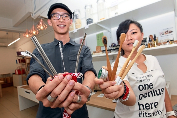 Nude owners Wilson Chin and Low showing some of the eco-friendly items sold at their store. (Right) Bottles filled with different types of detergents at Bring Your Own Bottle.