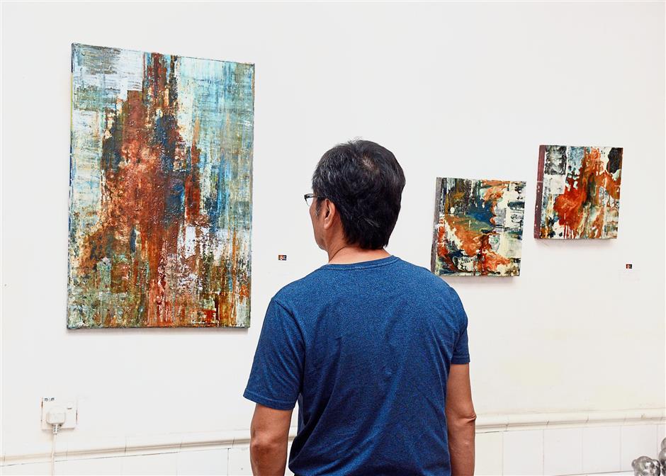A visitor viewing a piece from Maizul’s Gratify the Dogma series on the modern dependence on tech gadgets.