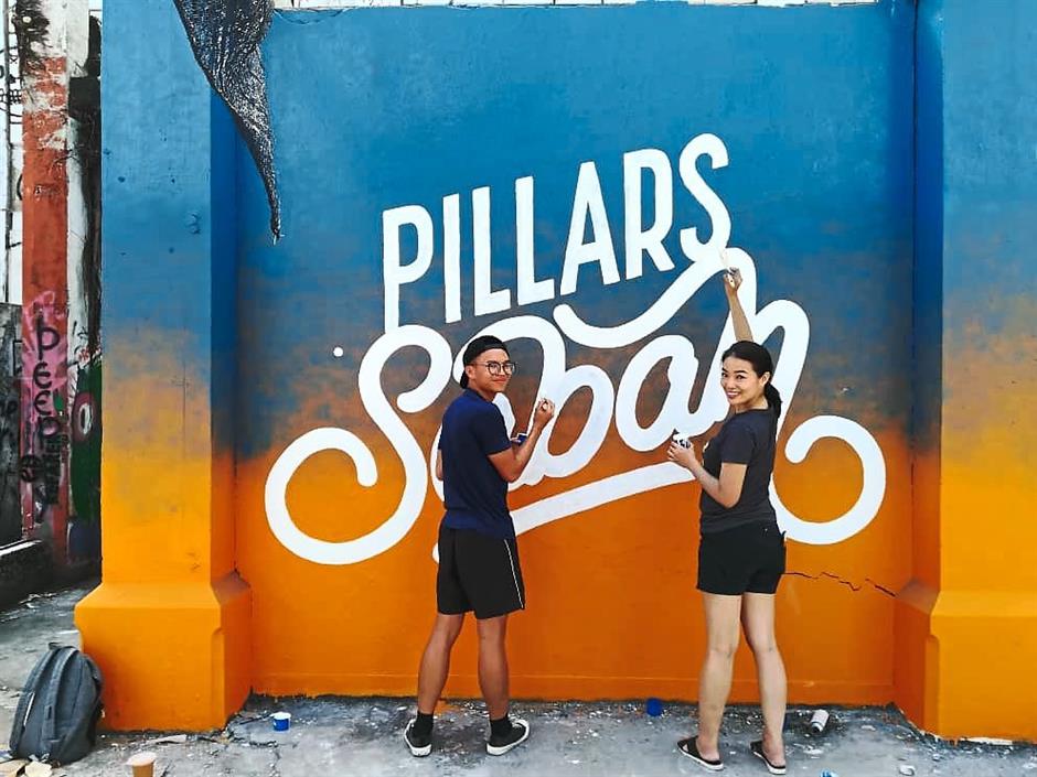 Artist Wilson Ng and Red painting the Pillars of Sabah mural at the Sabah Street Art Gallery. The mural was inspired by Sabahs sunset, which Red described as one of the best sunsets in the world.