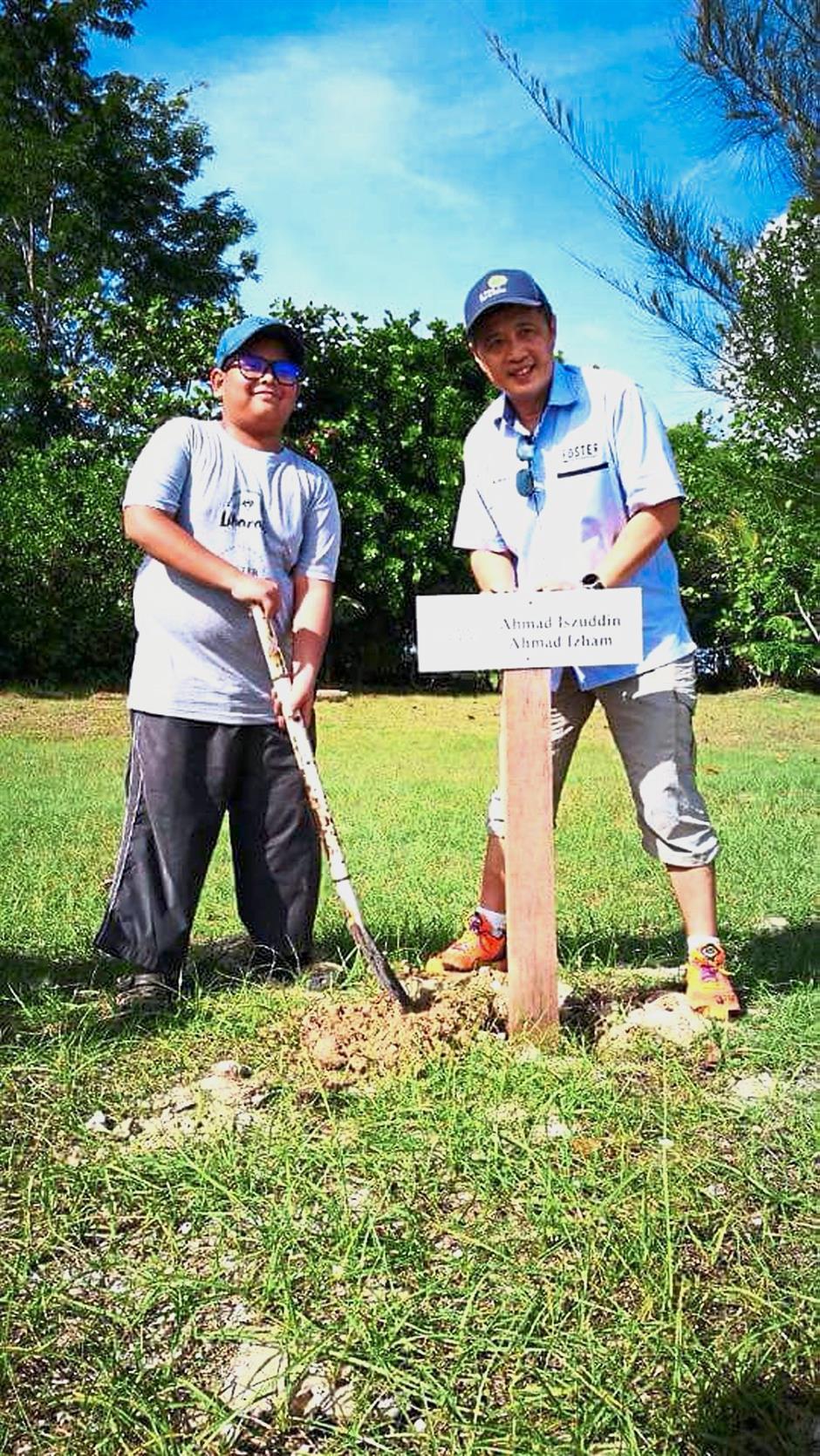 Iszuddin (left) and Yee putting up a signboard marking the 100m area adopted by the former.
