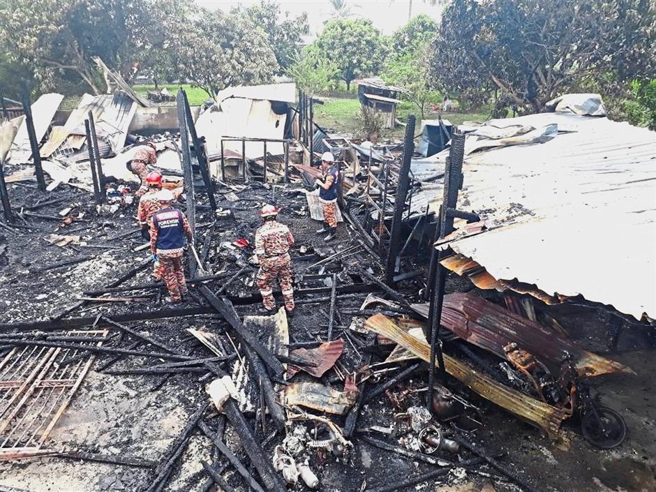 Devastating sight: Firefighters inspecting the razed wooden house in Tanjung Sepat.