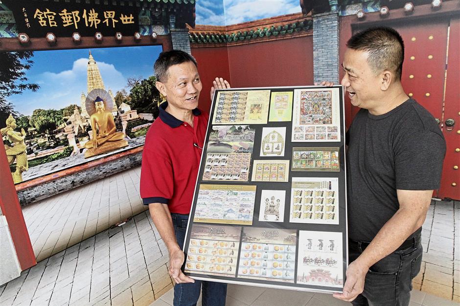 Hor (left) and Yeoh showing some of the stamps mounted on a frame for display at the gallery.