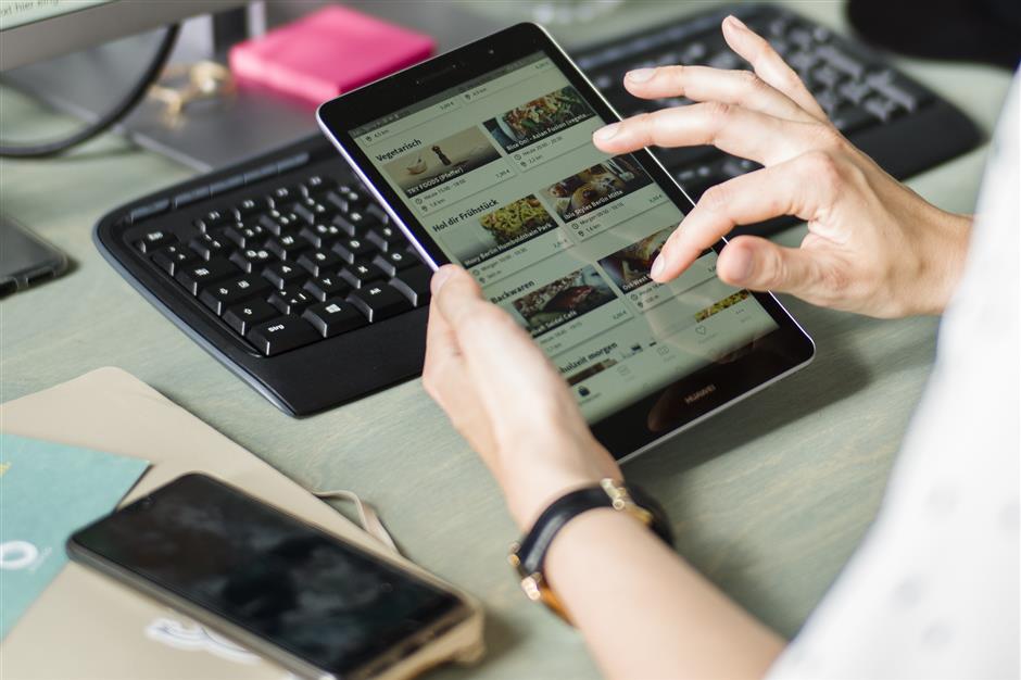 In this Tuesday, May 21, 2019 photo, Franziska Lienert spokeswoman of the company which runs the food sharing app 'Too Good To Go', uses a tablet to find a restaurant participating with the food sharing community, during an interview with the Associated Press in Berlin. In Germany, growing numbers of people use modern technology such as phone apps to help reduce food waste. In an effort to cut down on climate-wrecking carbon dioxide emissions created by food waste, they build online communities to share food before throwing it away. (AP Photo/Markus Schreiber)