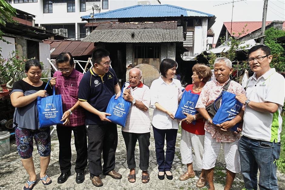 (From second left) Tanjong MCA secretary Datuk Lim Gim Soon, Tan, Ng(centre) and H’ng (right) giving out some dry rations to members of the families who are still living in the heritage building.