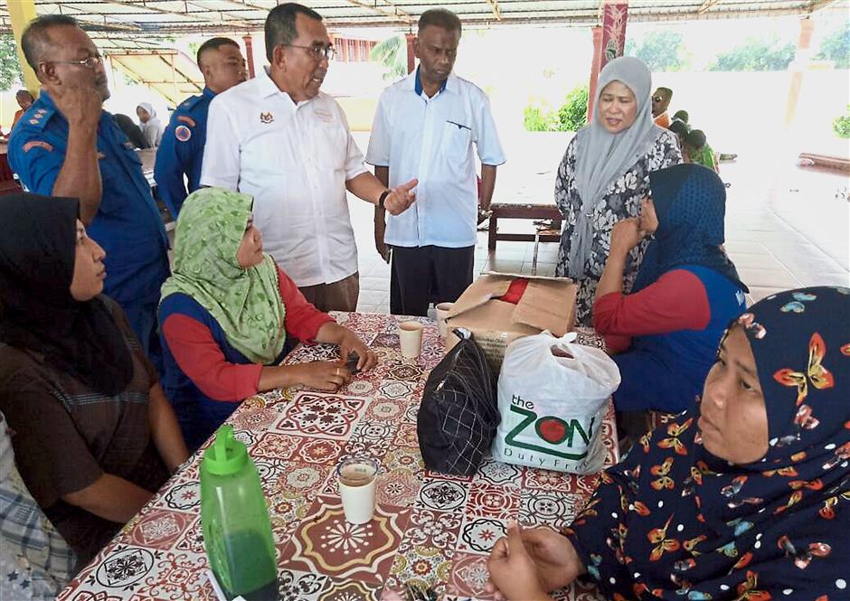 Xxxxx: ?Johari ?(standing-third left) ?with his wife Datin Seri Marziah Mohd Hashim (standing-right) and Kubang Pasu District Disaster Management secretariat’s secretary Kapten (Civil Defence) Kamalruzamal Kasa (standing-left) conversing with a few female flood victims at a ?flood relief centre?.