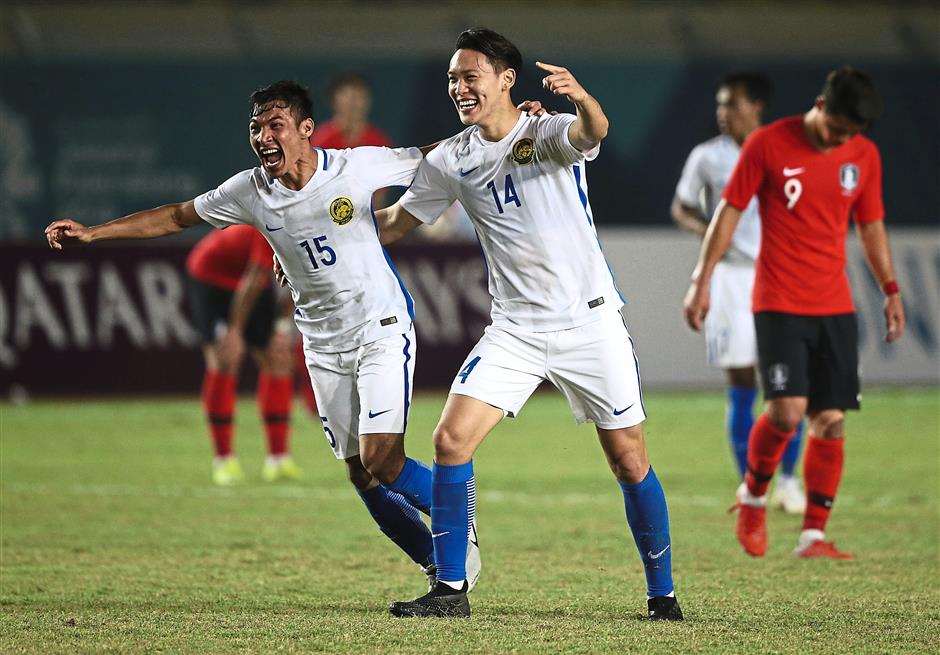 Malaysias Mohd Rizal Mohd Ghazali and teammate Dominic Tan, right, celebrate after they defeated South Korea 2-1 at the 18th Asian Games at Si Jalak Harupat Stadium in Bandung, Indonesia, Friday, Aug. 17, 2018. (AP Photo/ Achmad Ibrahim )