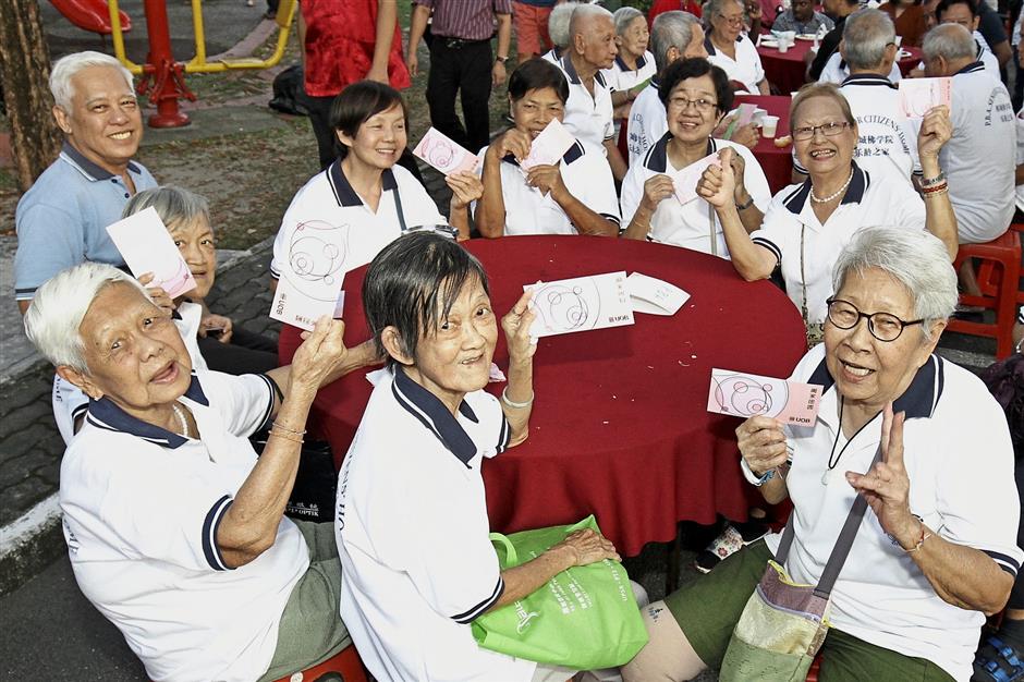 Residents from Happy Penang Buddhist Association Senior Citizens’ Home showing off the red packets they received at the event.