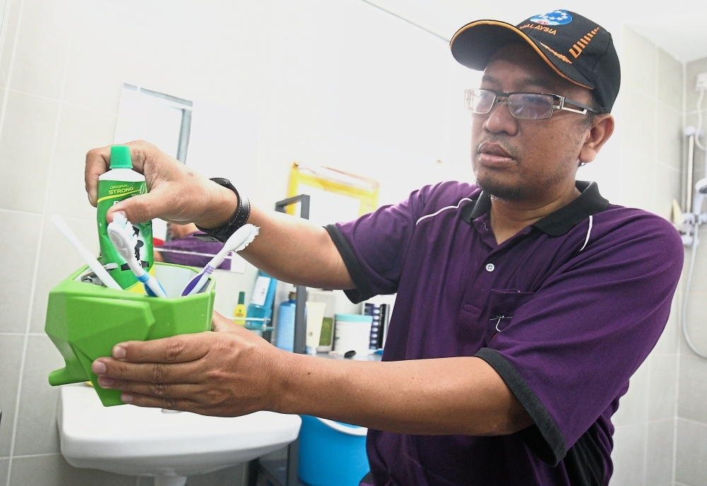 Ahmad checking a toothbrush container for Aedes mosquito larvae at a unit in Damai Apartment.