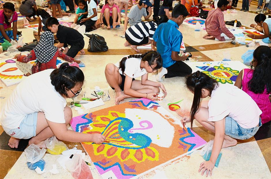 (From left) Gracelyn, Jia Xi and Yu Qi working on the kolam that would eventually land them second placing.