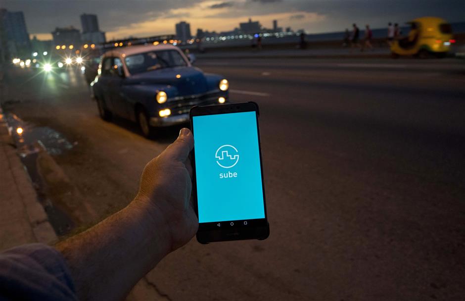 A man holds his phone showing the app 'Sube,' a ride-hailing app for the aging American sedans on the streets of Havana, in Havana, Cuba, Thursday, Feb. 21, 2019. In the 2 1/2 months since Cuba allowed its citizens internet access via cellphones, fast-moving changes are subtle but palpable as Cubans challenge government officials online, post photos of filthy school bathrooms and drag what was once of the world’s least-connected countries into the digital age.(AP Photo/Ramon Espinosa)