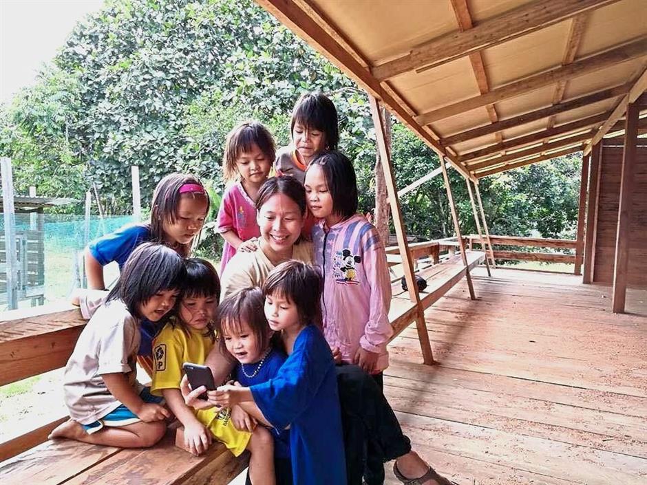 Wonderment: ?Chan showing a smartphone to Penan children at the new kindergarten building.