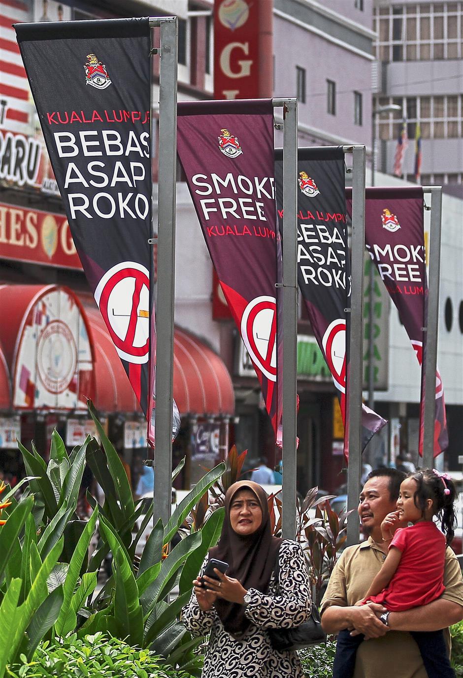 Raising awareness: People walking pass ‘Smoke-free Kuala Lumpur’ banners along a walkway in Kuala Lumpur. — Bernama