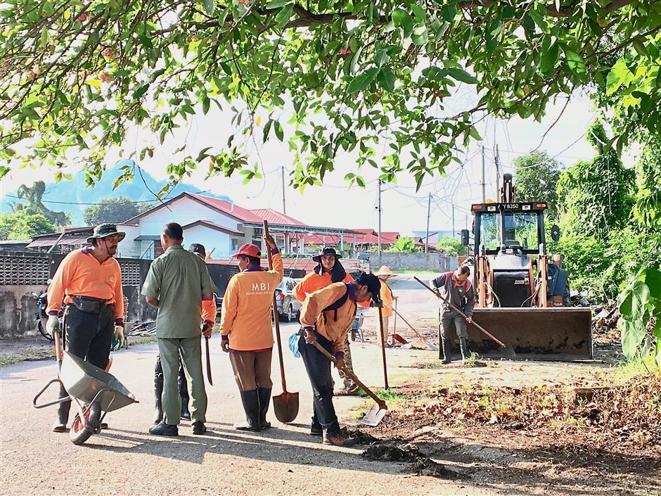 Ipoh City Council workers cleaning vegetation in the neighbourhood.
