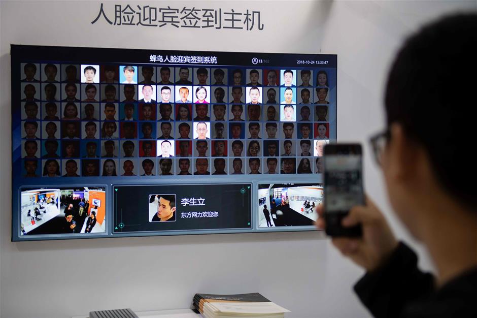 A visitor takes a photo with his smartphone of an AI (Artificial Inteligence) security camera system using facial recognition technology at the 14th China International Exhibition on Public Safety and Security at the China International Exhibition Center in Beijing on October 24, 2018. (Photo by NICOLAS ASFOURI / AFP)