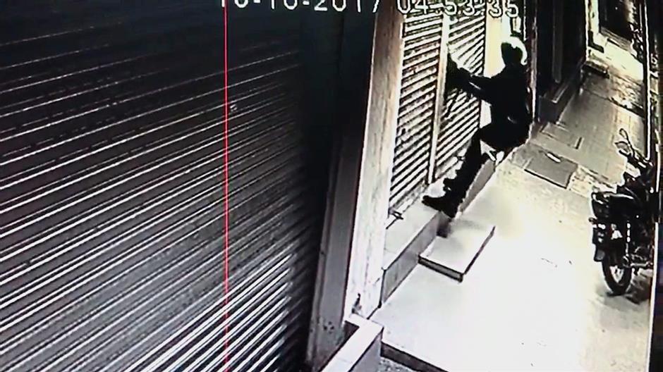 He uses force to break a section of the shutter.