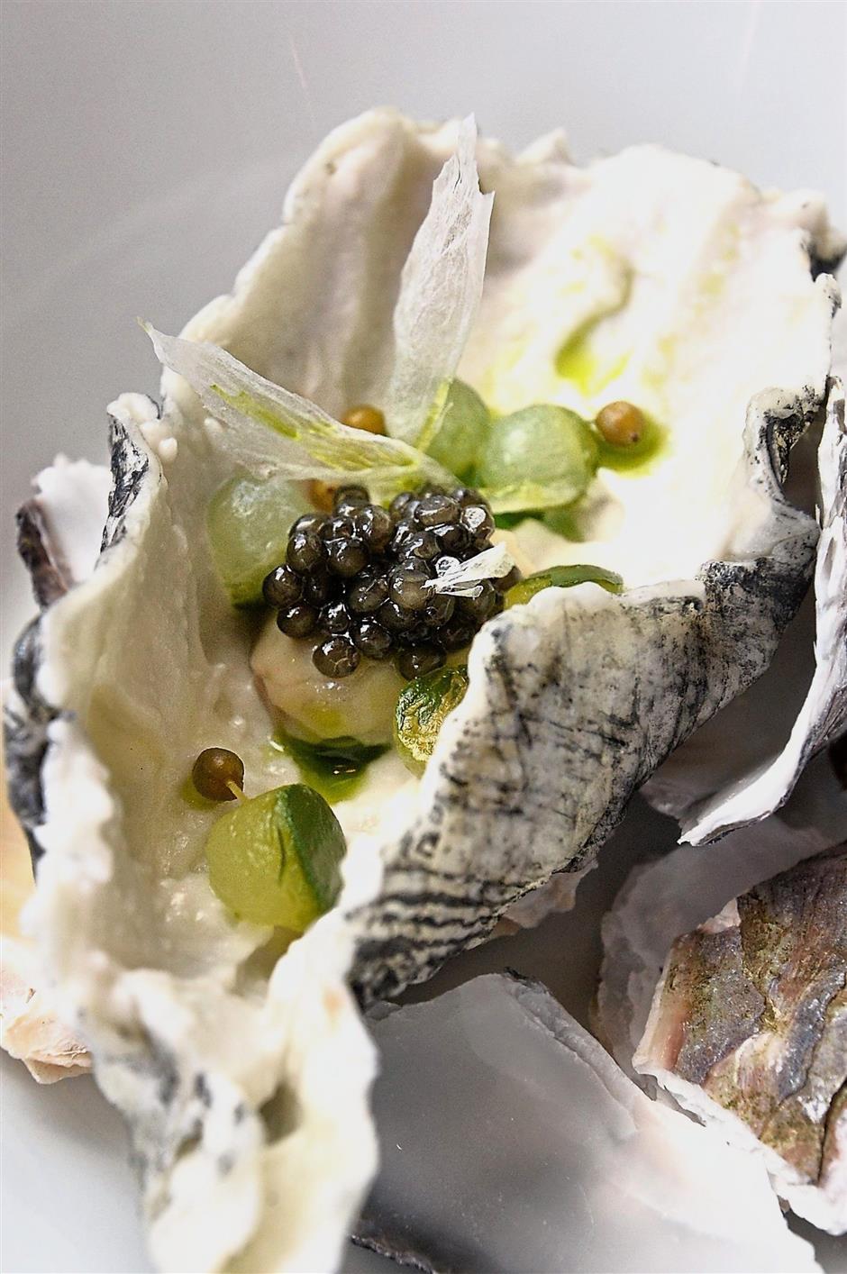 Oyster with preserved elderberries and oscietre caviar. The oyster shell replicated from rice and tapiaco flour is edible.