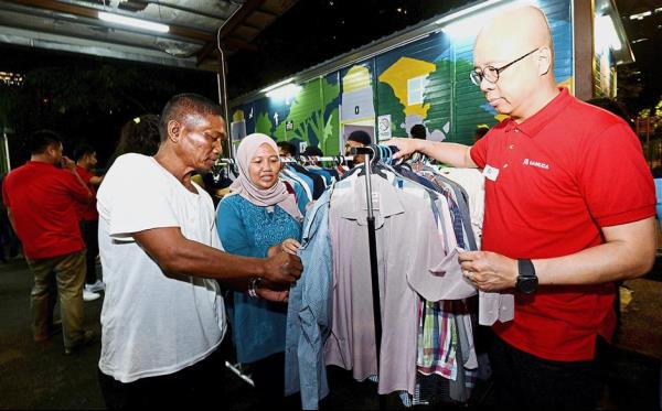 Doing the needful: Chan (right) and Dr Rusaslina helping former driver Jalaludin choose clothes at Kedai Jalanan.