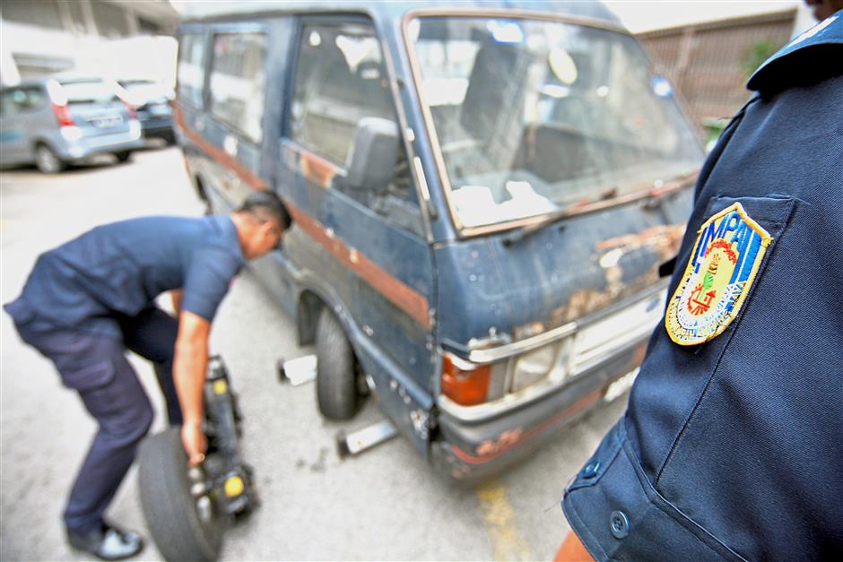 MPAJ enforcement officers preparing a dilapidated vehicle in Pandan Perdana to be towed away during a weekly operation. The council estimates that there are more than 1000 abandoned vehicles in the municipality.