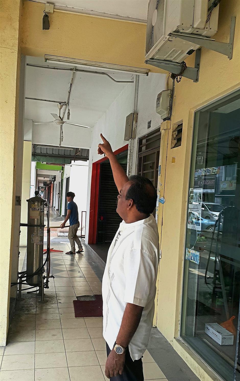 Treader R. Jeyakumar pointing at the cctv cameraa that has been damaged by the thief outside a pet shop that has been hit.