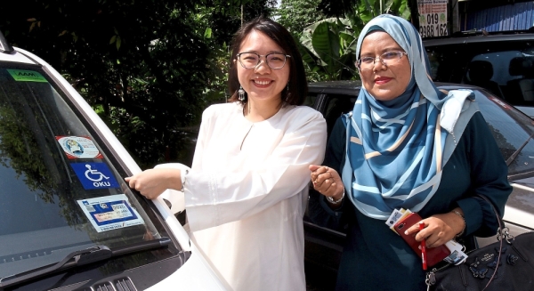 Jamaliah (left) showing the OKU sticker that is required for people to use parking bays for the disabled. With her is MBPJ City Planning assistant officer Nor Hanafiah Abdullah.