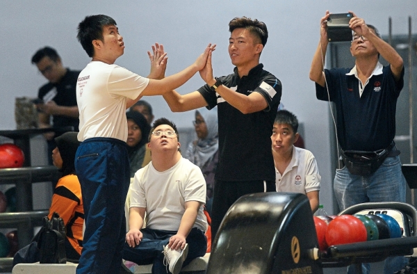 A special bowler celebrating with his partner after successfully dropping some pins.