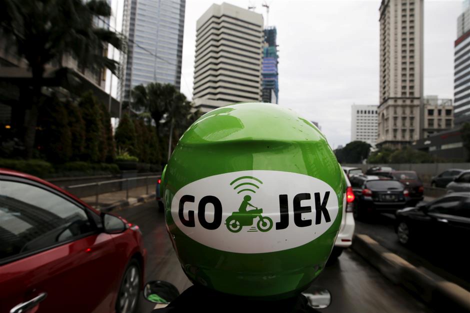 FILE PHOTO: A Gojek driver rides his motorcycle through a business district street in Jakarta,Indonesia, June 9, 2015. REUTERS/Beawiharta/File Photo