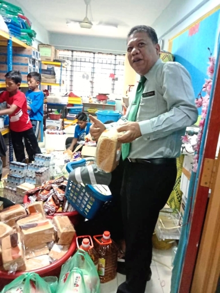 Zulkernai arranging food supplies donated by NGOs with his “children” at the foodbank he set up within the school.The food is distributed to the children every Friday so that they would not go hungry over the weekend.