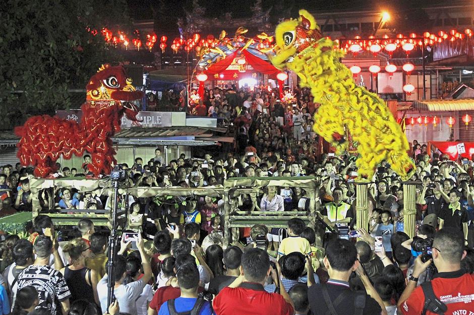 A crowd gathering to watch the exciting lion dance on stilts performance during the flame-watching ceremony.