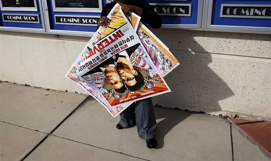 FILE - In this Dec. 17, 2014, file photo, a poster for the movie 'The Interview' is carried away by a worker after being pulled from a display case at a Carmike Cinemas movie theater in Atlanta. A computer programmer working for the North Korean government was charged with devastating cyberattacks that hacked Sony Pictures Entertainment and unleashed the WannaCry ransomware virus that infected computers in 150 countries and crippled parts of the British health care system, federal prosecutors said Thursday, Sept. 6, 2018. U.S. officials believe the Sony hack was retribution for 'The Interview,' a comedy starring Seth Rogen and James Franco in a plot to assassinate North Korea's leader, Kim Jong Un. (AP Photo/David Goldman, File)