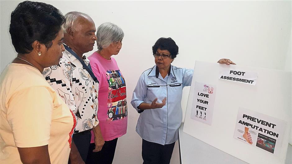 Hands on: Gnanam briefing patients and cutting (far right) the toenails of a patient at the Diabetes Malaysia office in Taman Chi Liung, Klang.