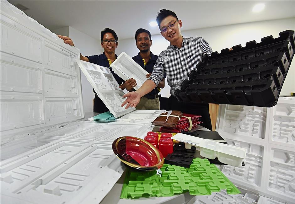 Green element: Danapacs R&D head Louis Lee (right) shows off its trays made through more environmentally-friendly processes for various use.