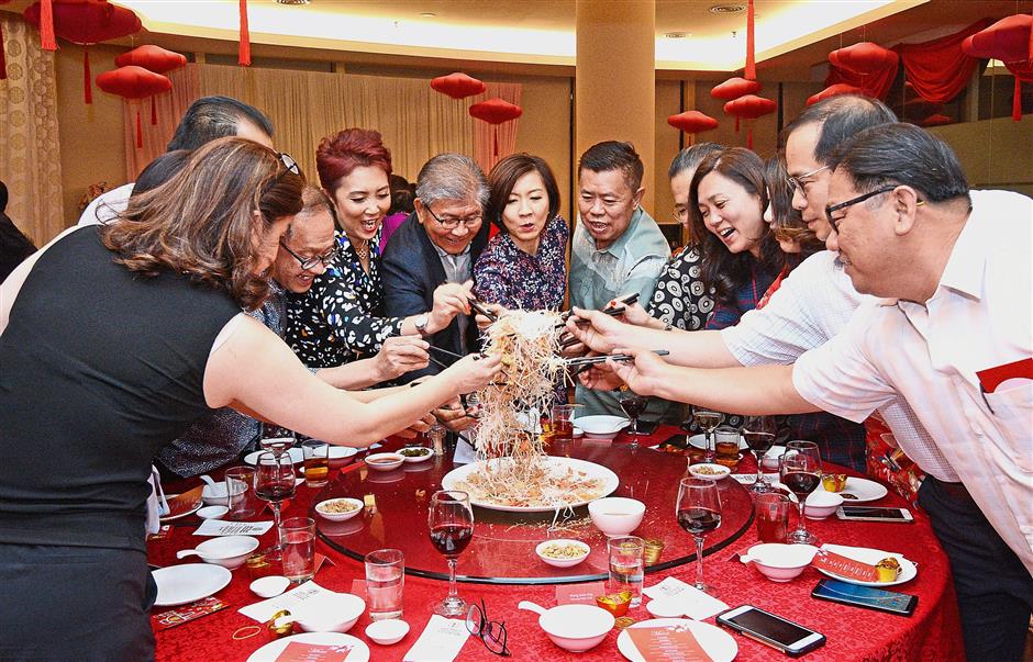 Hunza Group’s top management including founder Khor (middle, in coat), tossing yee sang with representatives of the local media during the Media Appreciation Night 2019 at Jade Palace in Gurney Paragon Mall.
