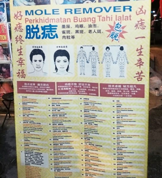 Banner advertising services at a mole removal stall set up in a night market.