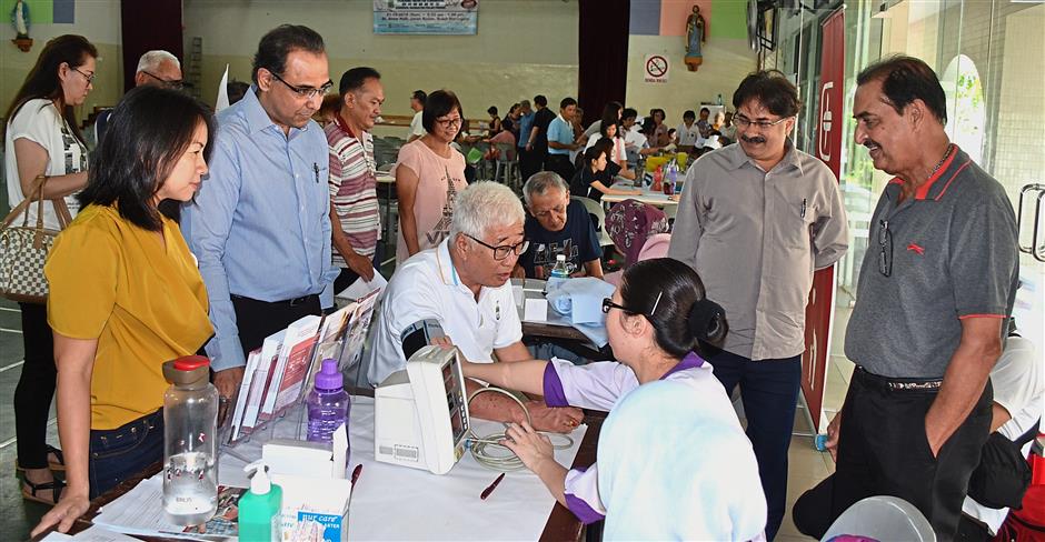 (Left) Dr Teoh examining the eye of an elderly patient. (Below) Phee having his blood pressure checked during the Penang Health Carnival at the St Anne’s Hall in Jalan Kulim, Bukit Mertajam. Looking on are (from left) Heng, Dr Ajay, Dr Paramjit and Dr Kulwaran. — Photos: M. SIVANANTHA SHARMA/The Star