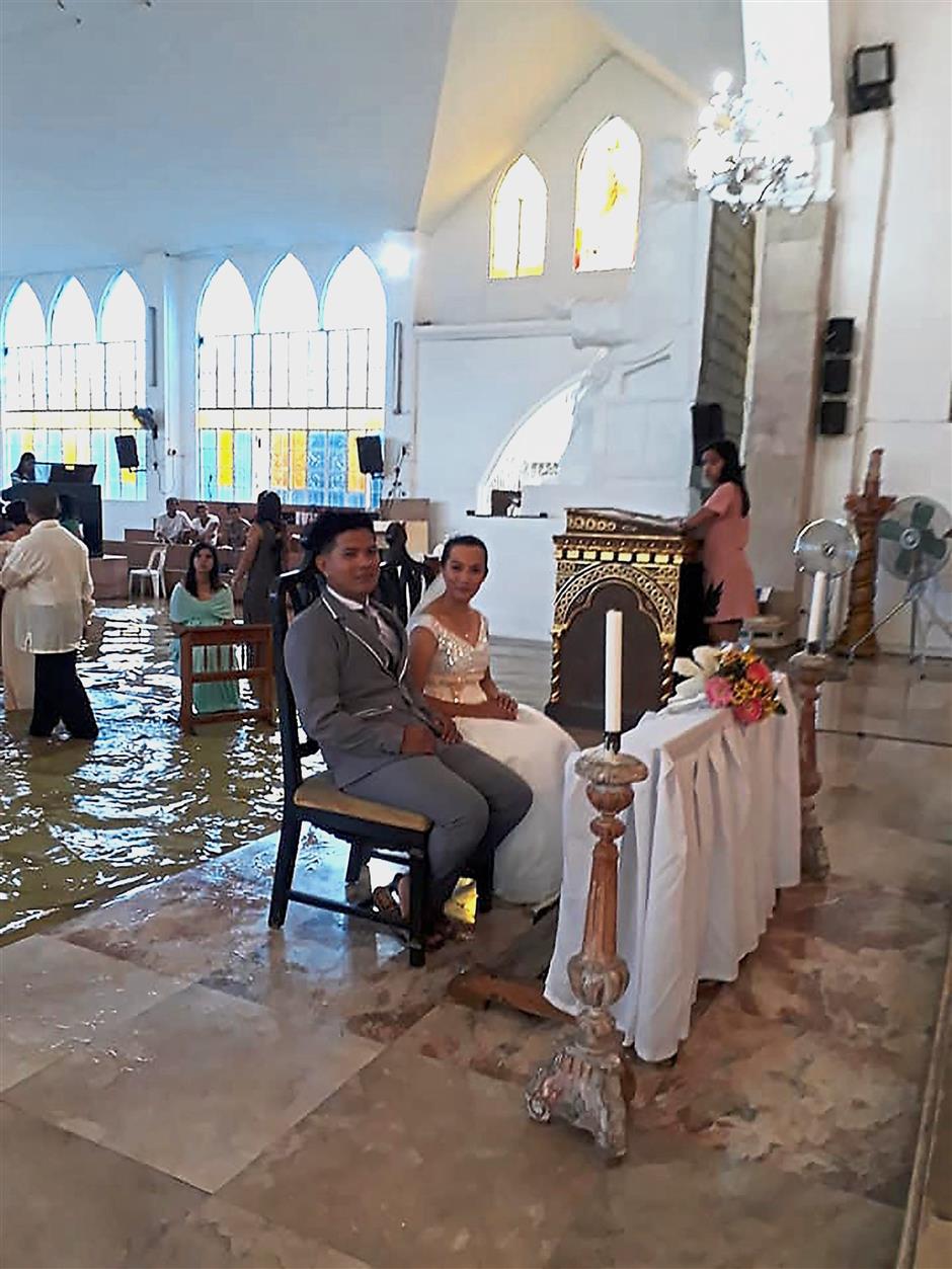 For wetter or worse: Delos Angeles and her groom during their wedding at a flooded church in Hagonoy town, north of Manila. — AFP
