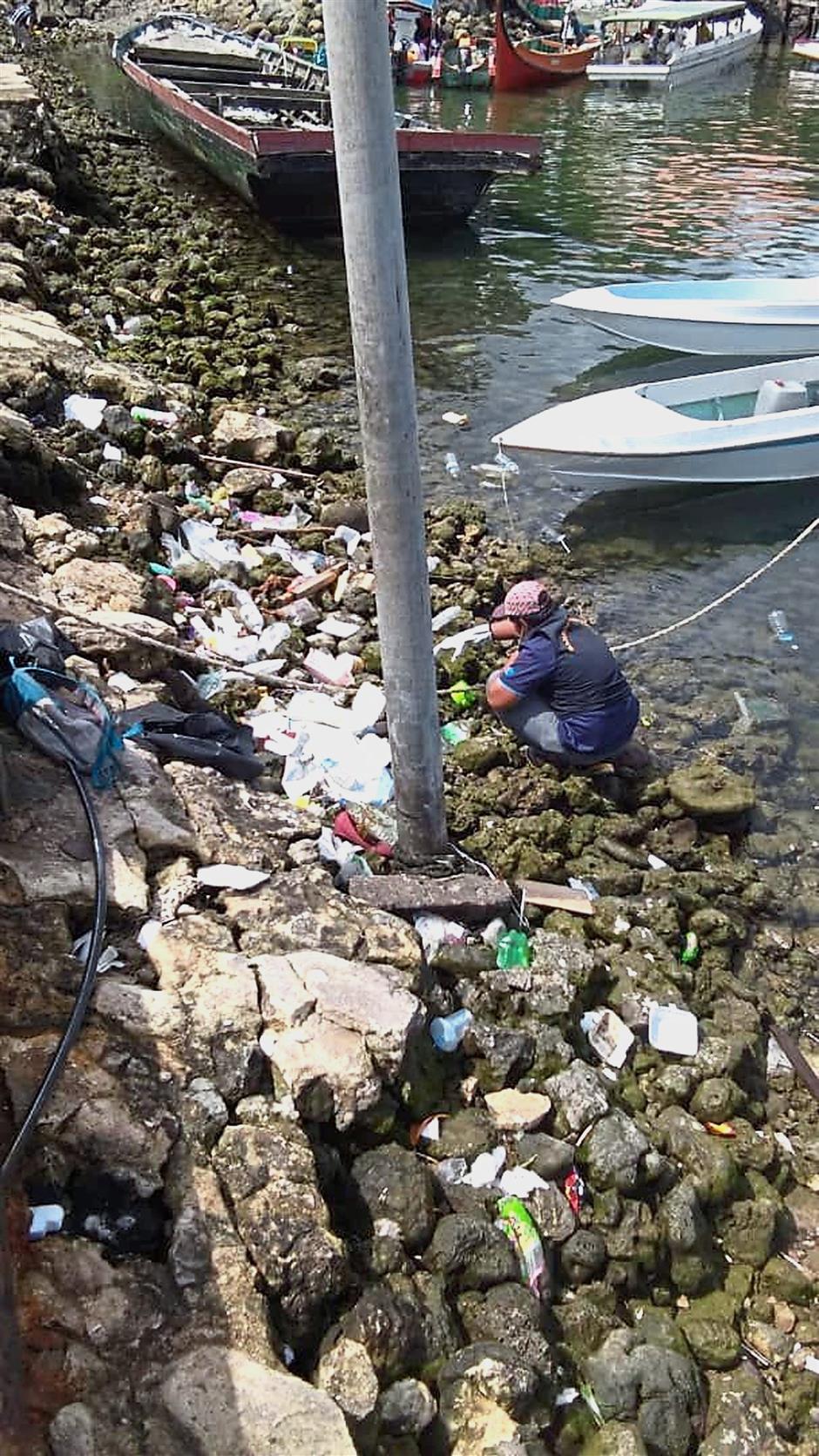 Cleaning the filth: A cleaner picking litter of plastics and other rubbish in Semporna during a campaign to clean the town over the past week.