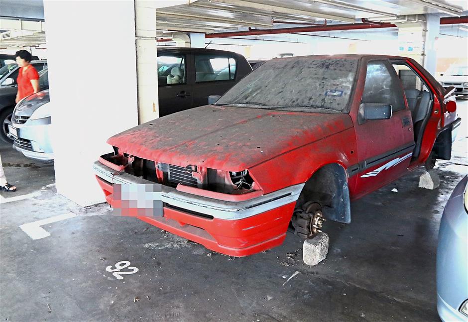 This car without wheels is occupying a parking lot at the Kompleks Farlim car park.