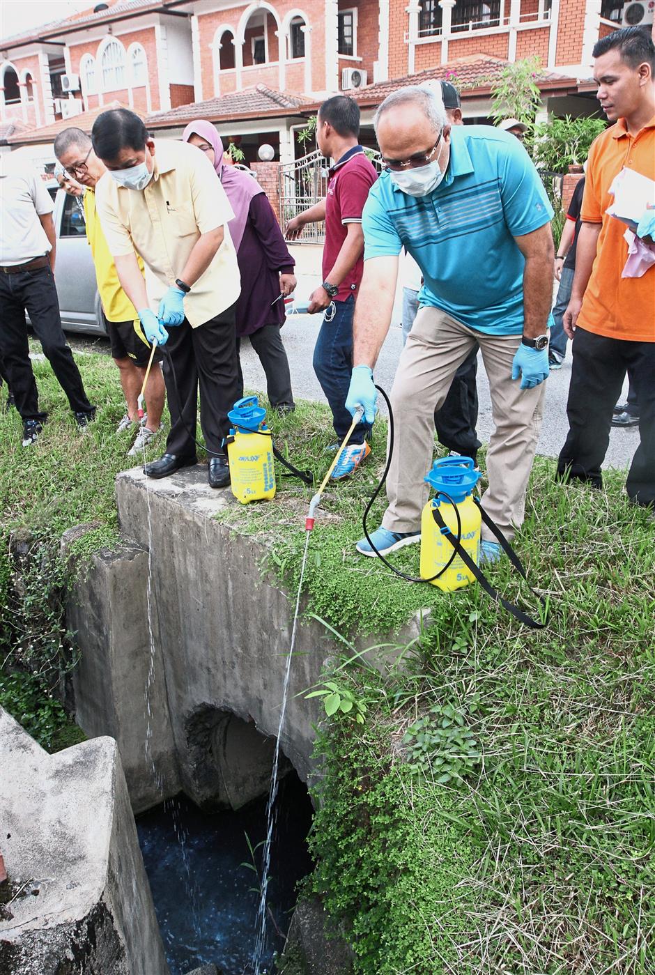 Hee (left) and Mohd Sayuthi spraying larvicide into the drains around Bandar Sungai Long Section 4.